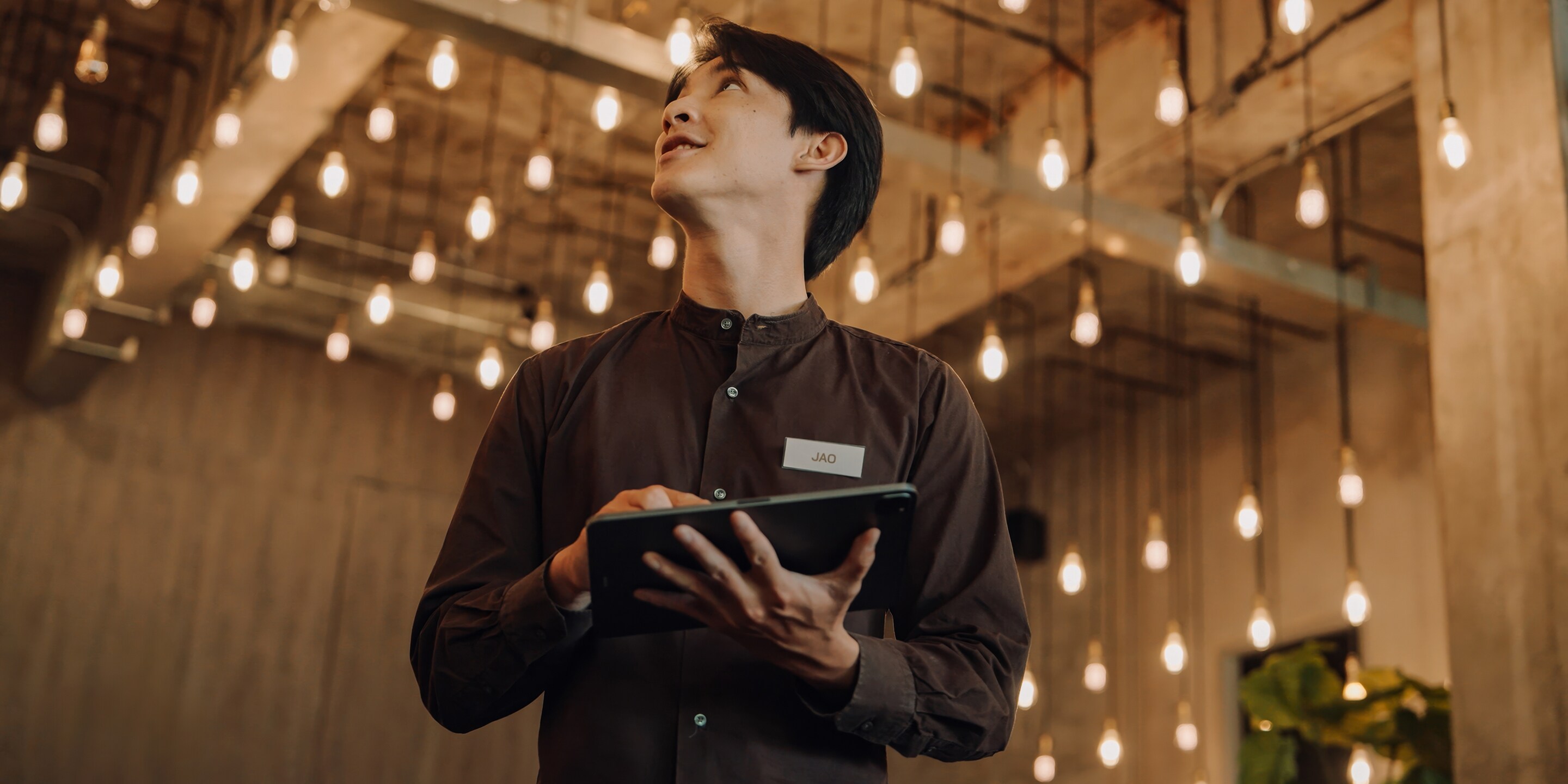 Hostel Staff Use digital tablet to Check and Adjust Energy  in a Modern, Stylish Interior with Ambient Lighting